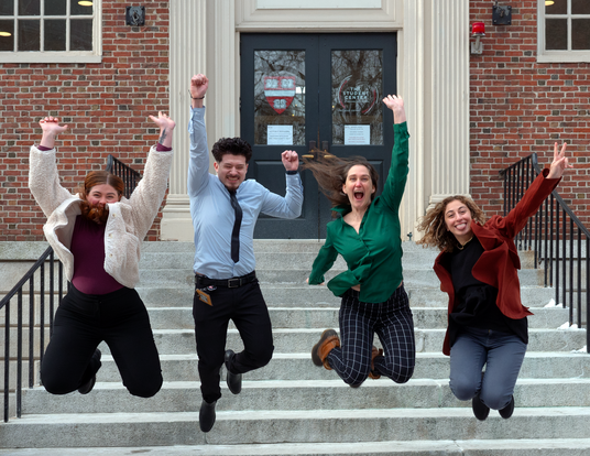 Student services staff laughing and jumping off steps of Lehman