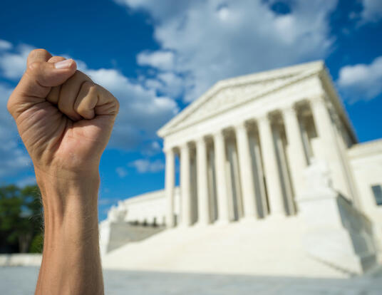Hand clenched in fist symbol as sign of protest in front of US Supreme Court building in Washington DC.