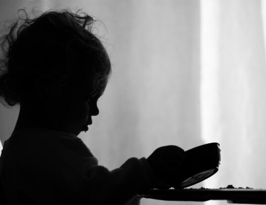 A little girl is sadly looking into her empty bowl