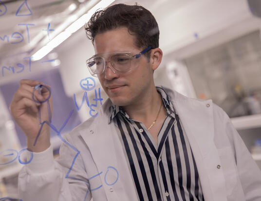 Jose in lab writing on transparent wall