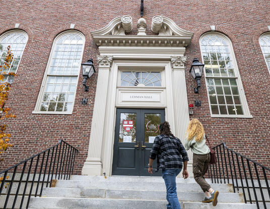 exterior of Lehman Hall with two students walking in the main doors