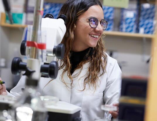 Maria in her lab coat smiling behind equipment