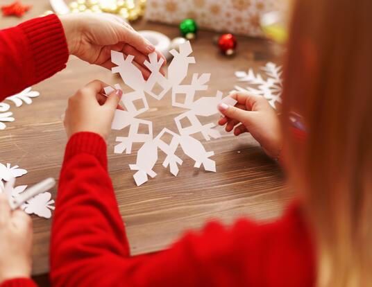 child hands holding a paper snowflake and other crafts