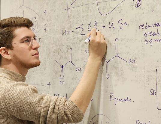 Ozturk writing formulas on a white board