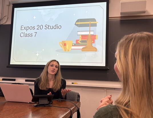 Presiozo sitting in front of screen and teaching students