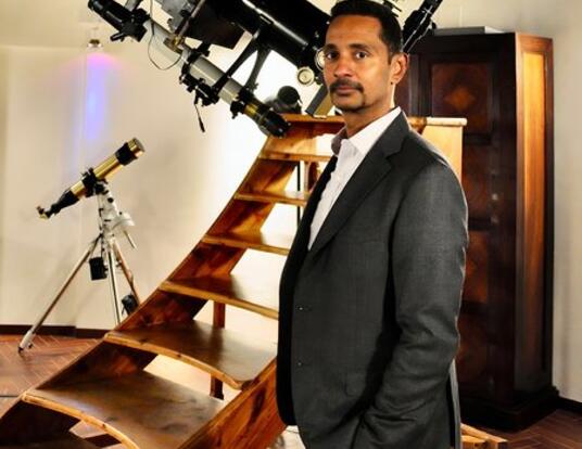Ray Jayawardhana, PhD '00, standing next to a telescope at the Vatican Observatory