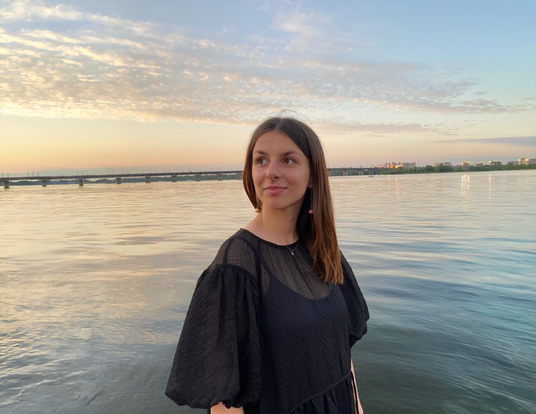 Anastasiia looking to the side with water and sunset behind her