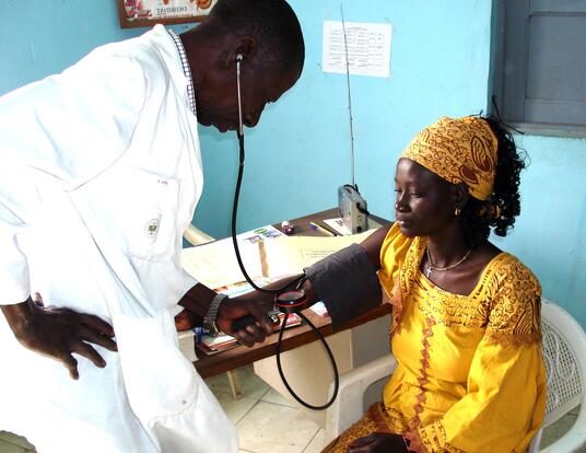 Senegalese medical professional checking a patient's blood pressure.