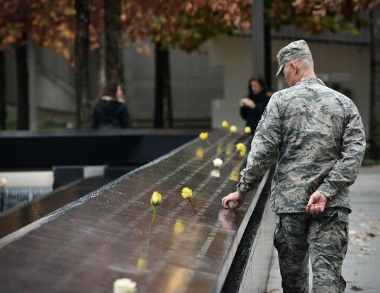 Man in military uniform looks and holds onto 9/11 memorial 