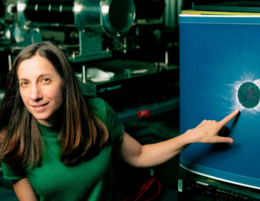 Astrophysicist Jenna Samra pointing at an image of the sun