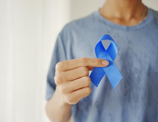 person holding blue prostate cancer ribbon