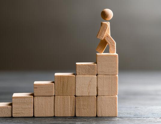 wooden blocks with wooden person climbing to the top