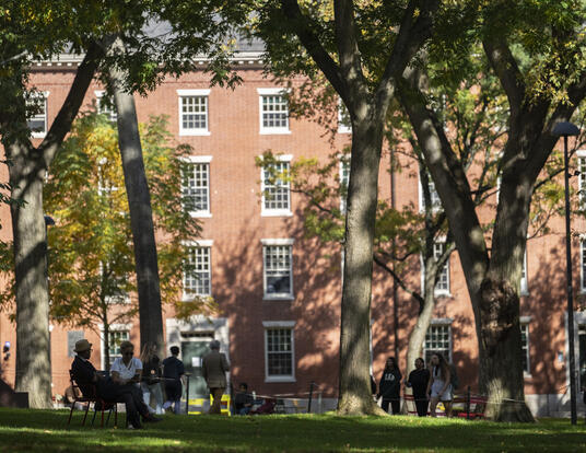 shot of campus in the fall; brick buildings with trees and students walking around