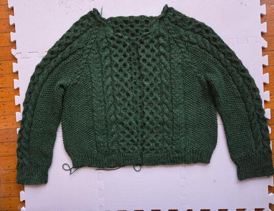 green knitted wool sweater, with some loose ends