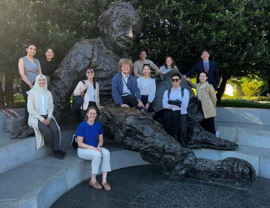 group of students sit along the large Albert Einstein statue in Washington, D.C.