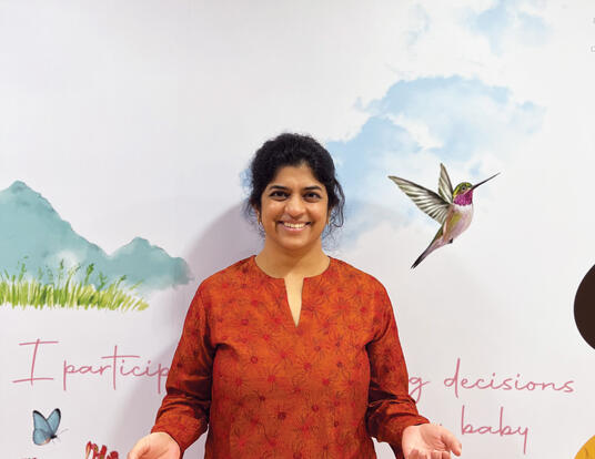Nilekani poses in front of artwork in Aastrika Midwifery Centre