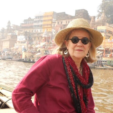 Diana Eck wearing sunglasses and hat with city in background 