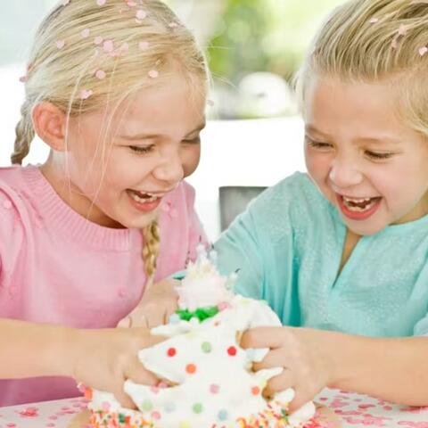 Photo of laughing girls dividing up a cake with their bare hands 