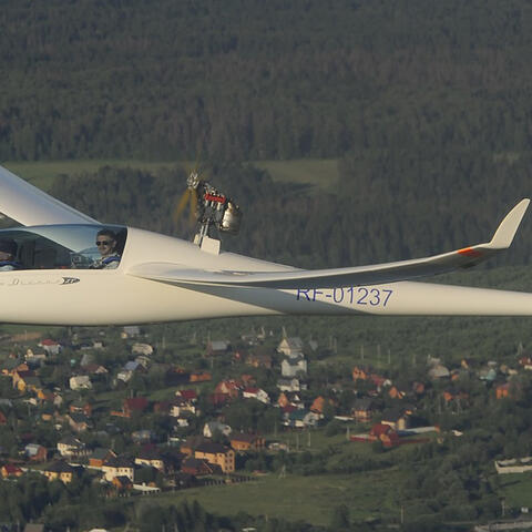 Glider in flight over small town