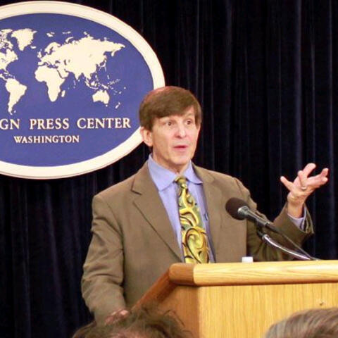 Allan Lichtman standing at podium with American flag in the background