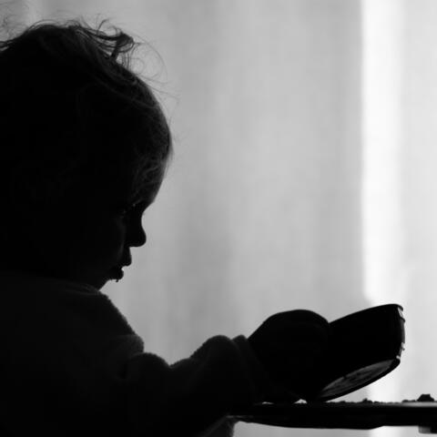 A little girl is sadly looking into her empty bowl
