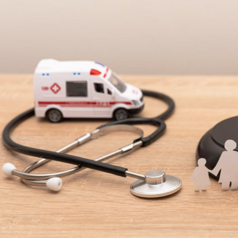 Stock photo of miniature ambulance, stethoscope, and gavel on a wood tabletop