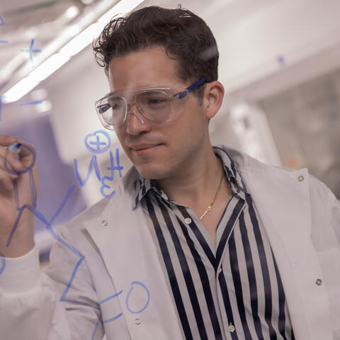 Jose in lab writing on transparent wall