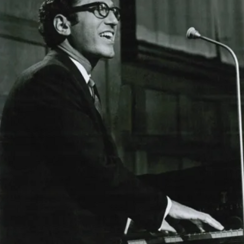 Black and white photo of Tom Lehrer at the piano
