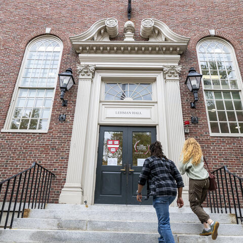 exterior of Lehman Hall with two students walking in the main doors