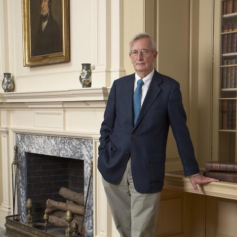 Dr. Keith Thompson standing to the right of a marble fireplace