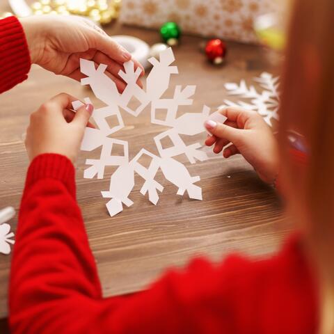 child hands holding a paper snowflake and other crafts