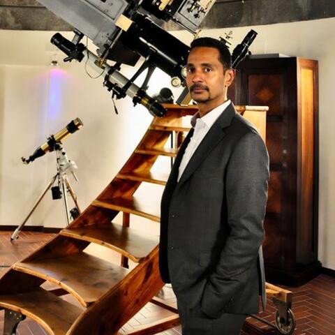 Ray Jayawardhana, PhD '00, standing next to a telescope at the Vatican Observatory