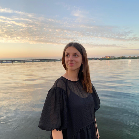 Anastasiia looking to the side with water and sunset behind her