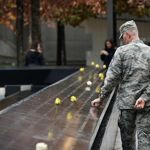 Man in military uniform looks and holds onto 9/11 memorial 