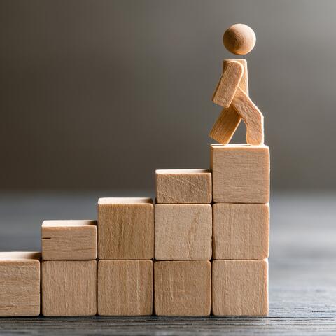 wooden blocks with wooden person climbing to the top