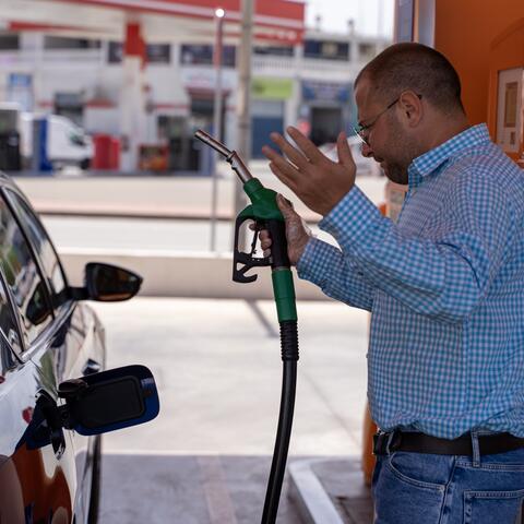guy standing at gas pump seemingly frustrated