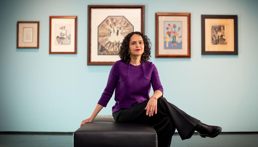 Cecile Fromont sitting on chair in Locke Gallery in front of teal wall with pictures hanging 