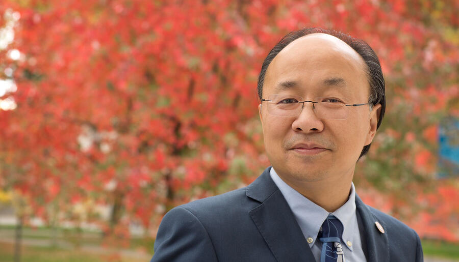 Professor Xiao-Li Meng in front of tree with red leaves