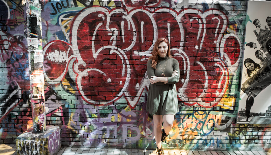 Samantha Hawkins stands against a wall filled with graffiti