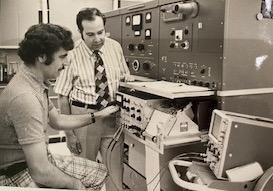 Black and white photo of two men with a machine