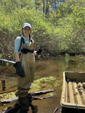 Heidi Pickard posing for a photo in the Quashnet River on Cape Cod, MA where she collected fish using an electrofishing method.