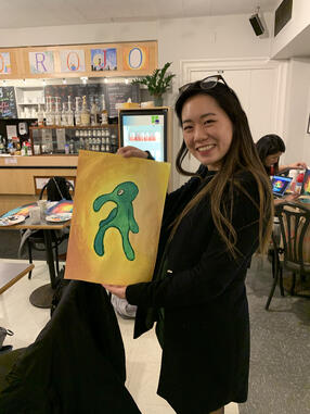 Betty Hu holding a painting in Cafe Gato Rojo