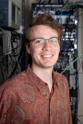 Pieter-Jan Stas standing in lab in front of electric control rack