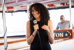 Emma Ebowe holding a microphone on a cruise