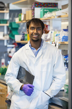 Ananthan Sadagopan in lab coat in a lab with purple gloves