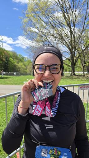 Maria holding a medal after running a marathon