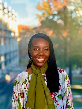 Headshot of Atte Kadoma wearing a floral shirt and green scarf
