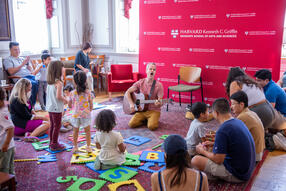 Children's music performer singing and playing the guitar to group of children and adults