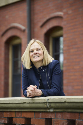 Image of Dean Dench in front of a brick academic building