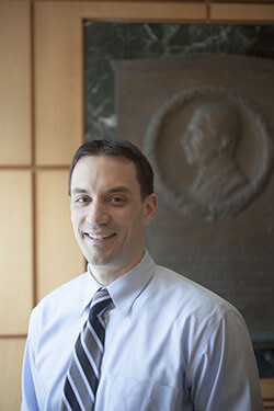 Allen Aloise in front of a granite memorial